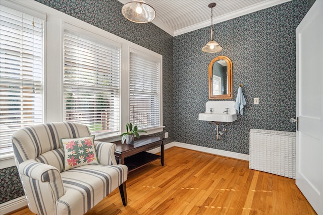 living area featuring hardwood / wood-style flooring, sink, and ornamental molding