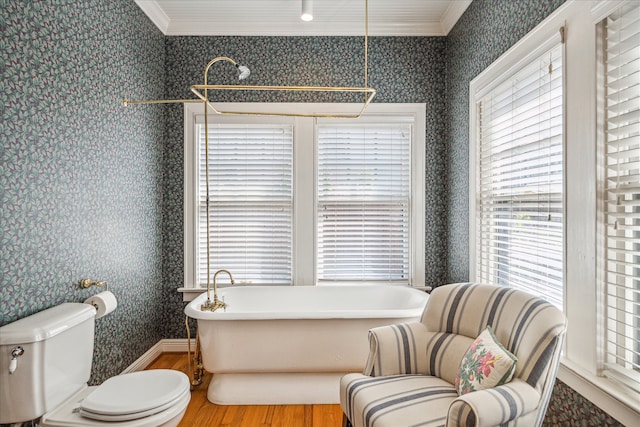 bathroom with a wealth of natural light, hardwood / wood-style floors, ornamental molding, and a tub