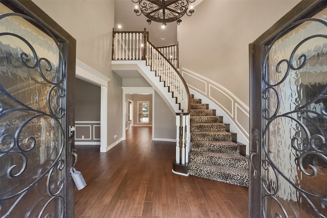 foyer entrance with dark wood-type flooring, a high ceiling, and an inviting chandelier