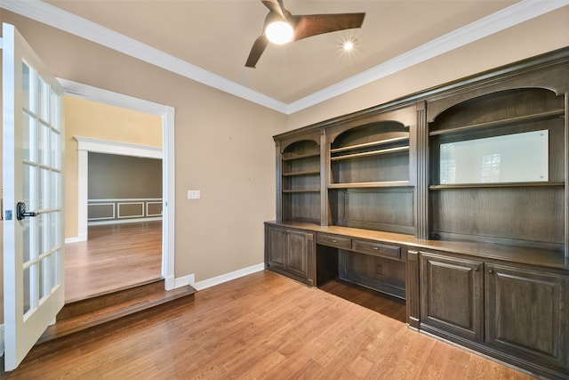 unfurnished office featuring ceiling fan, wood-type flooring, built in desk, and ornamental molding