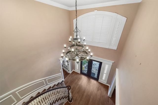 entryway featuring dark wood-type flooring, a chandelier, french doors, and crown molding