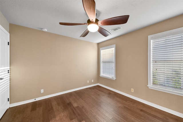 empty room featuring ceiling fan, a textured ceiling, and dark hardwood / wood-style flooring