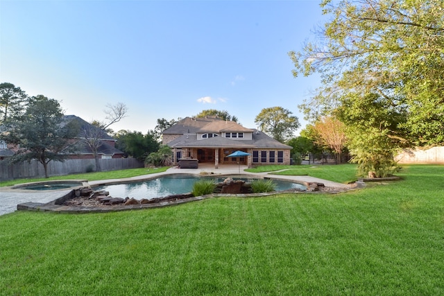 back of property featuring a lawn, a swimming pool with hot tub, and a patio area