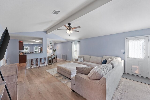 living room featuring radiator, ceiling fan, light hardwood / wood-style flooring, and lofted ceiling with beams