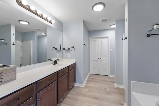 bathroom with hardwood / wood-style floors, vanity, and plus walk in shower