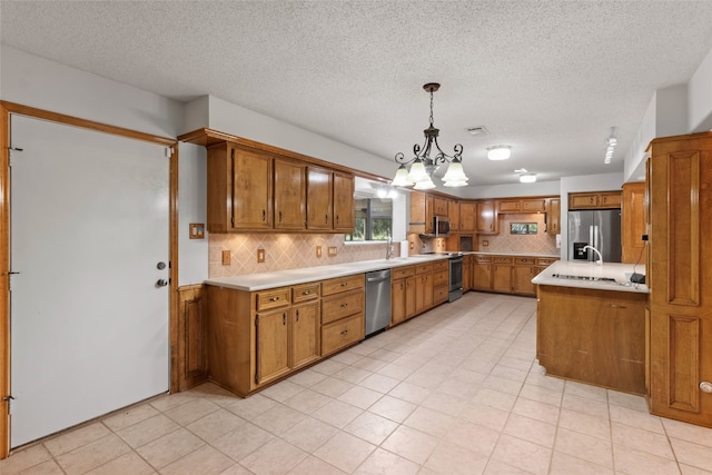 kitchen with backsplash, stainless steel appliances, hanging light fixtures, and a textured ceiling