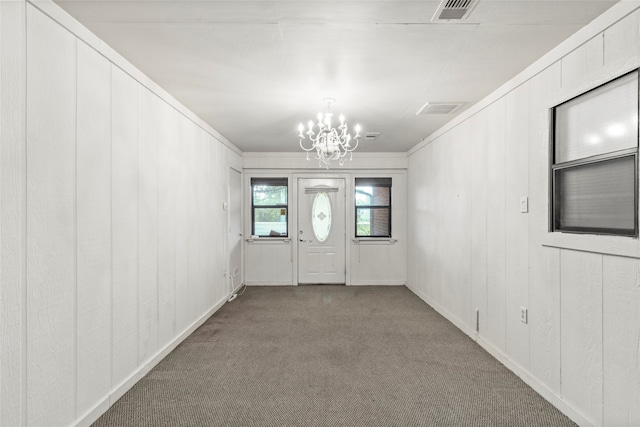 foyer with crown molding, carpet floors, and a notable chandelier