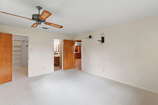 unfurnished bedroom with ceiling fan, a closet, a walk in closet, and ensuite bath