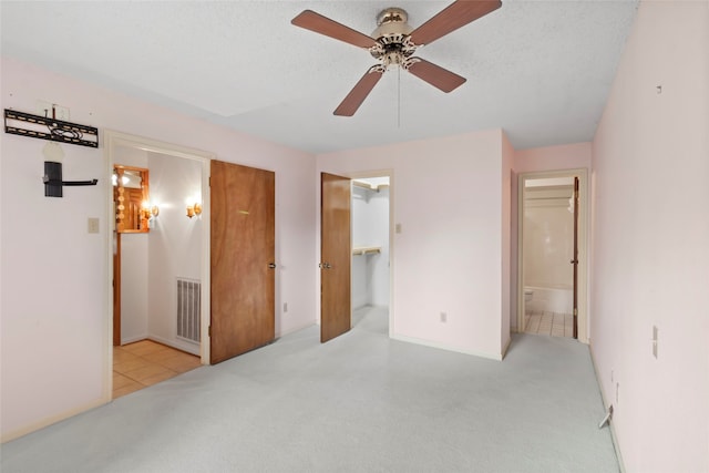 bedroom featuring a textured ceiling, ceiling fan, a spacious closet, connected bathroom, and a closet