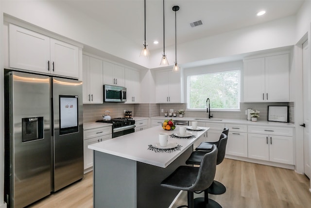 kitchen featuring white cabinetry, stainless steel appliances, backsplash, a breakfast bar area, and a kitchen island