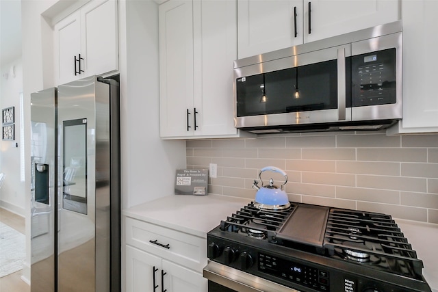 kitchen featuring white cabinets, decorative backsplash, and stainless steel appliances