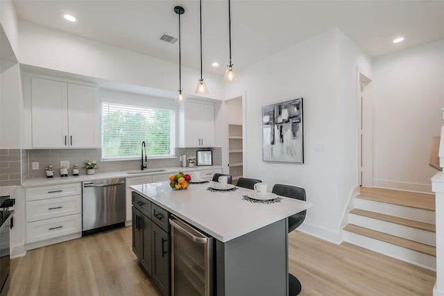 kitchen with backsplash, white cabinets, sink, stainless steel dishwasher, and beverage cooler