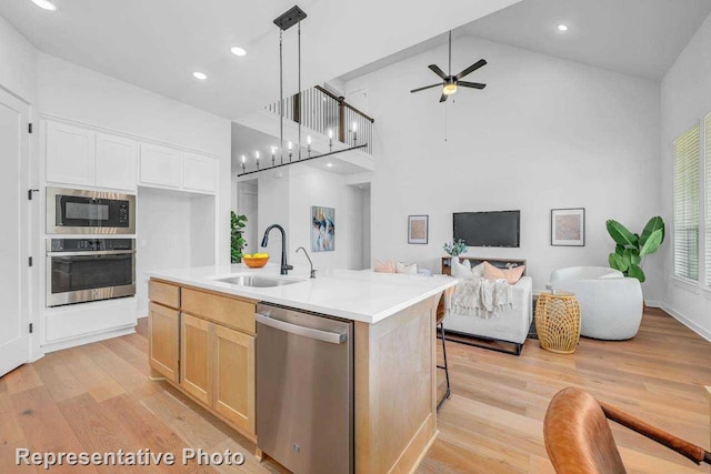 kitchen featuring decorative light fixtures, sink, a kitchen island with sink, high vaulted ceiling, and stainless steel appliances