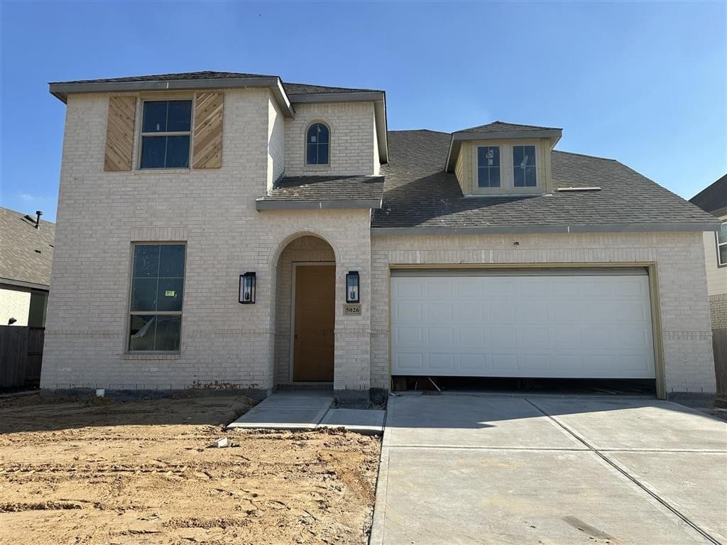 view of front of property featuring a garage, concrete driveway, and brick siding