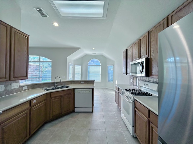 kitchen with lofted ceiling, sink, a healthy amount of sunlight, and stainless steel appliances