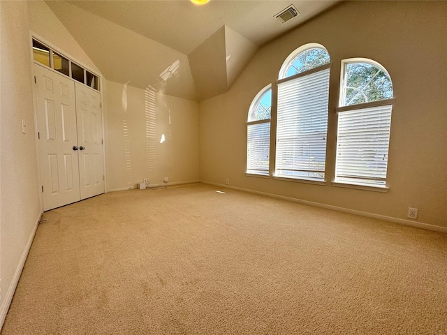 unfurnished room with vaulted ceiling, carpet, visible vents, and baseboards