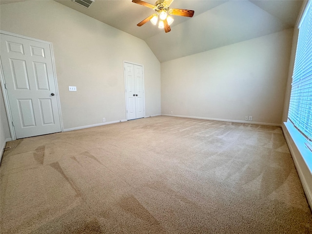 unfurnished room featuring lofted ceiling, ceiling fan, carpet flooring, visible vents, and baseboards