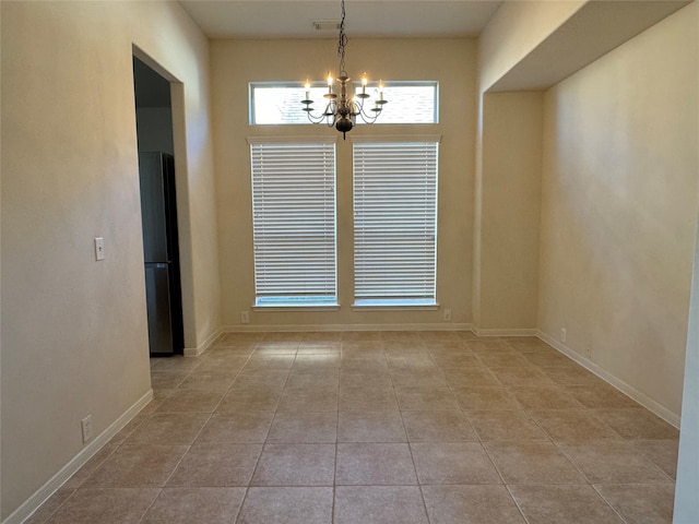 spare room featuring baseboards, light tile patterned flooring, and a notable chandelier