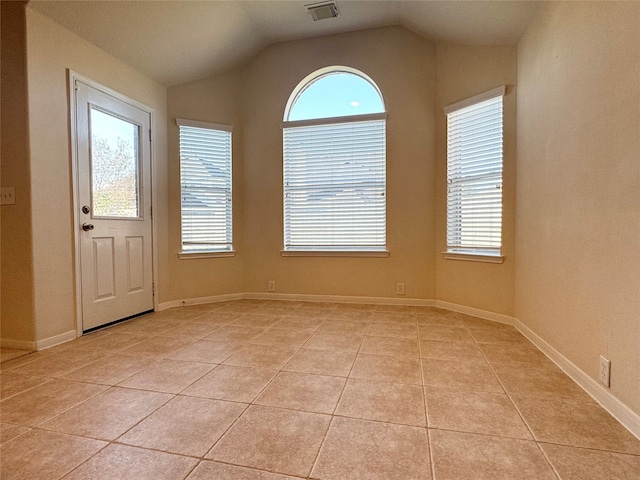 unfurnished room with lofted ceiling, visible vents, plenty of natural light, and light tile patterned flooring