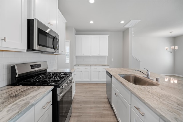 kitchen featuring white cabinetry, stainless steel appliances, sink, and light stone counters