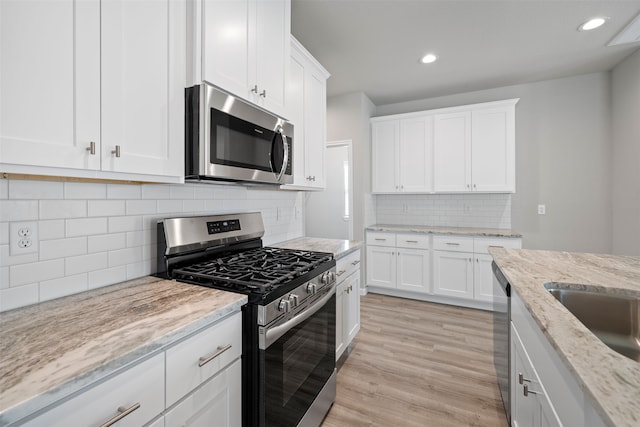 kitchen with white cabinetry, stainless steel appliances, and light stone counters