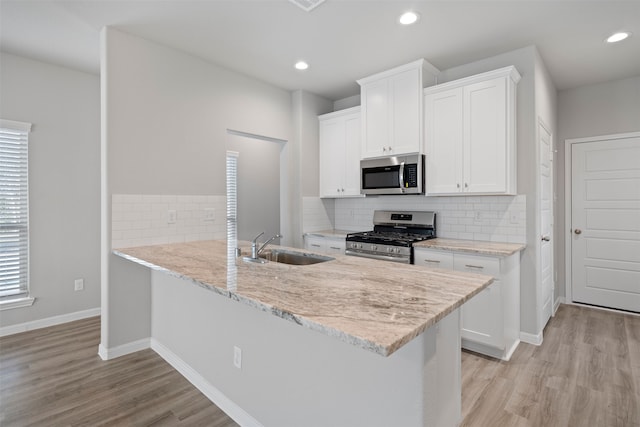 kitchen featuring stainless steel appliances, light hardwood / wood-style floors, white cabinets, and kitchen peninsula