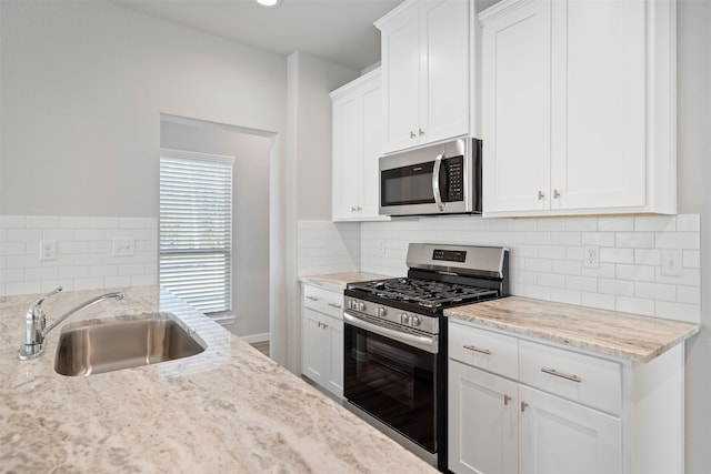 kitchen featuring white cabinetry, stainless steel appliances, sink, and light stone countertops