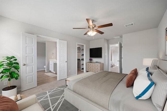 bedroom featuring ensuite bathroom, ceiling fan, a walk in closet, a closet, and light wood-type flooring