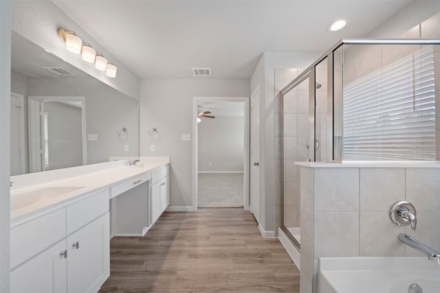 bathroom with shower with separate bathtub, vanity, wood-type flooring, and ceiling fan