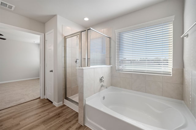 bathroom with shower with separate bathtub, hardwood / wood-style flooring, and ceiling fan