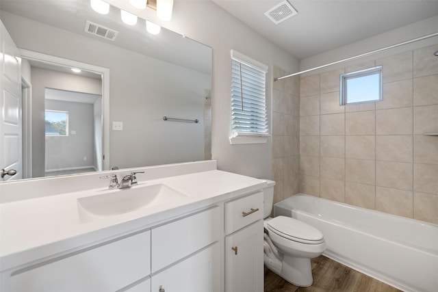 full bathroom featuring wood-type flooring, plenty of natural light, toilet, and tiled shower / bath