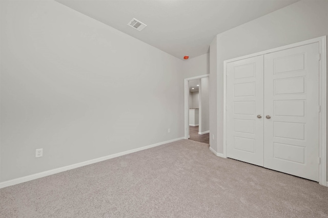 unfurnished bedroom featuring a closet and light colored carpet