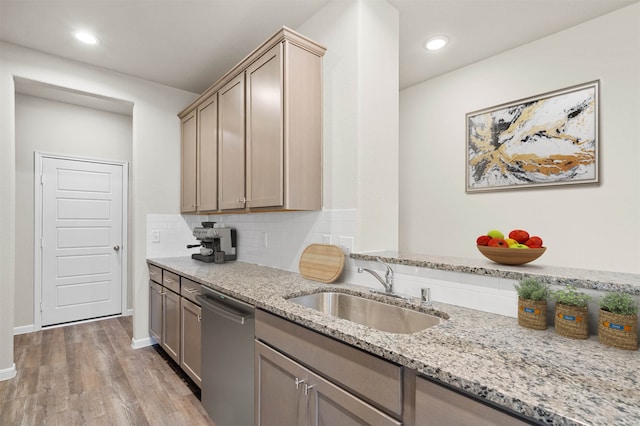 kitchen with light hardwood / wood-style floors, light stone counters, sink, stainless steel dishwasher, and backsplash