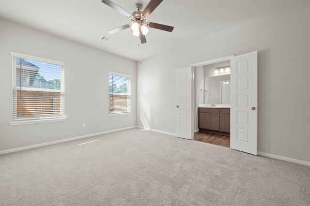 unfurnished bedroom featuring carpet floors, ceiling fan, and ensuite bathroom