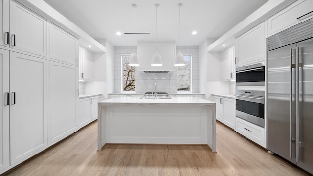 kitchen featuring pendant lighting, appliances with stainless steel finishes, white cabinetry, and a center island