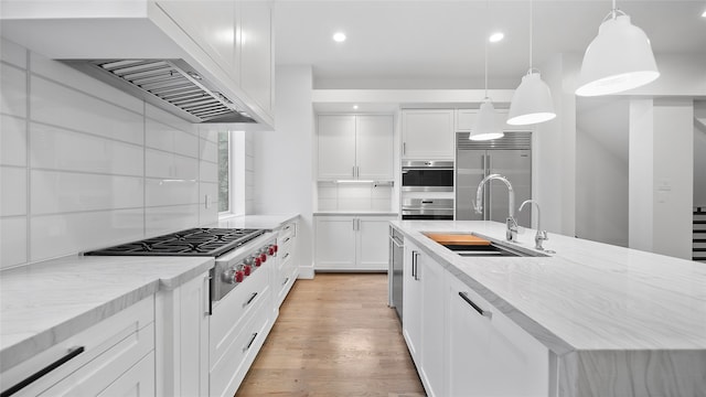 kitchen featuring sink, white cabinetry, decorative light fixtures, and stainless steel appliances