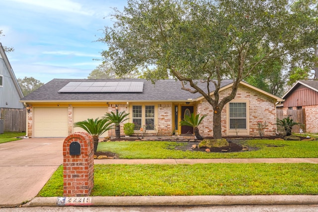 view of front of house featuring a garage, solar panels, and a front yard