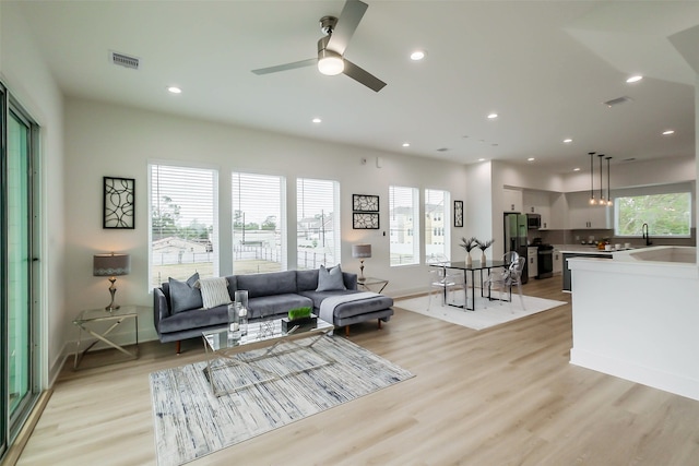 living room featuring light wood-type flooring, a wealth of natural light, sink, and ceiling fan