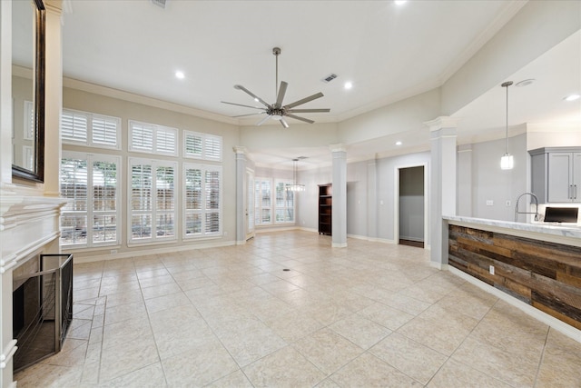 living room with sink, decorative columns, crown molding, light tile patterned flooring, and ceiling fan with notable chandelier