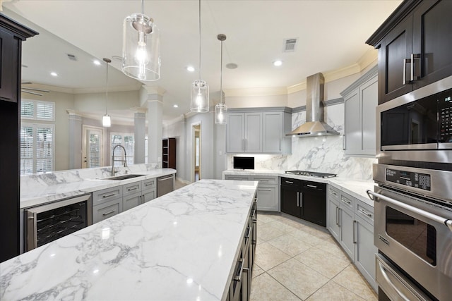 kitchen with sink, stainless steel appliances, wall chimney range hood, tasteful backsplash, and pendant lighting