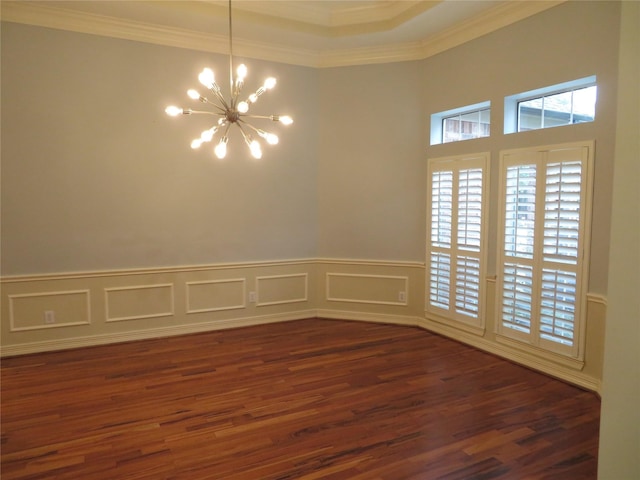 spare room featuring dark hardwood / wood-style flooring, ornamental molding, and a chandelier