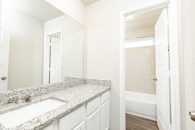 bathroom featuring wood-type flooring, tiled shower / bath combo, and vanity