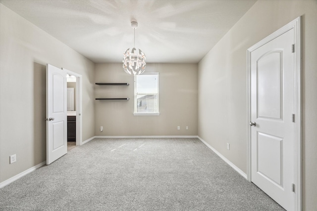 empty room with light colored carpet and a chandelier