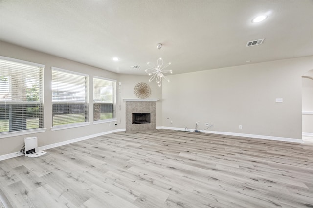 unfurnished living room with light wood-type flooring and a chandelier