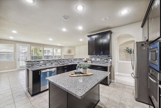 kitchen featuring sink, kitchen peninsula, appliances with stainless steel finishes, a kitchen island, and decorative backsplash