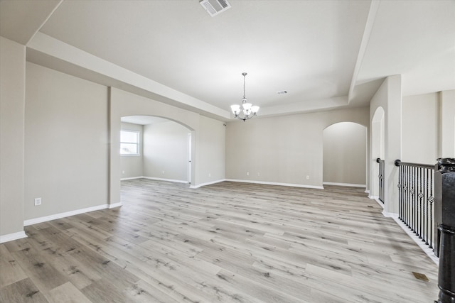 empty room featuring an inviting chandelier and light hardwood / wood-style flooring