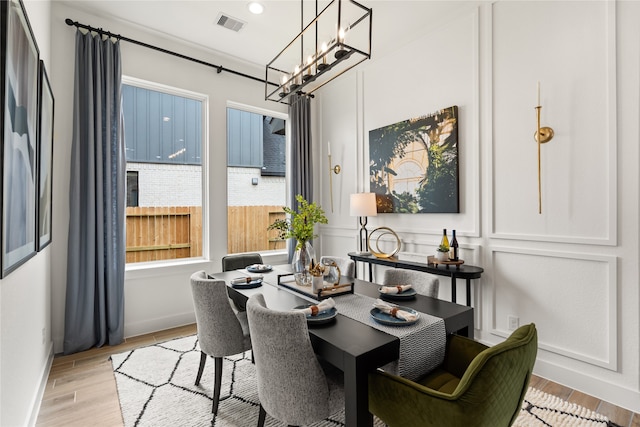 dining space with a notable chandelier, ornamental molding, and light hardwood / wood-style flooring