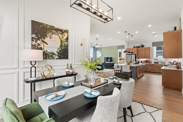 dining room featuring ceiling fan, light wood-type flooring, plenty of natural light, and sink