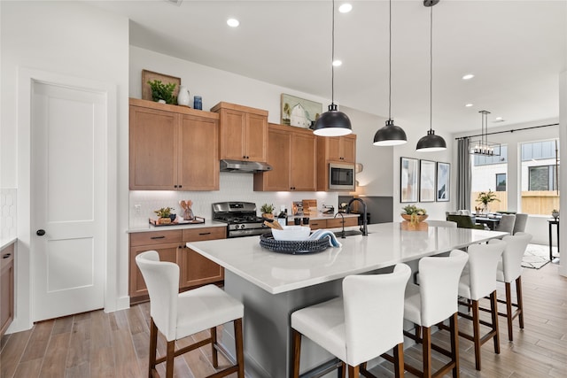 kitchen featuring a kitchen bar, stainless steel gas range, built in microwave, a spacious island, and pendant lighting