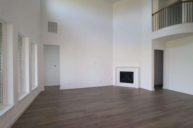 unfurnished living room featuring dark hardwood / wood-style flooring and a towering ceiling